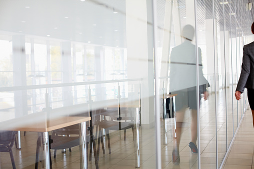 Reflection of businesswoman walking along the office corridor