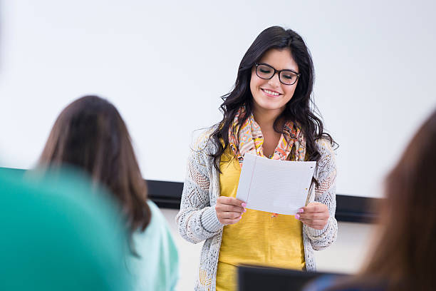 istock Hip young woman reading report to college class 521971159