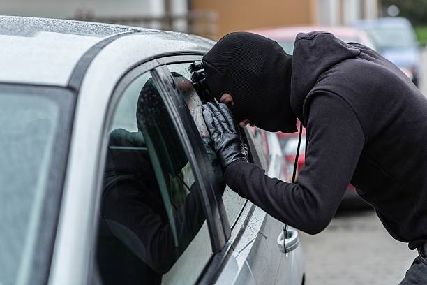 Car thief looking through car window stock photo