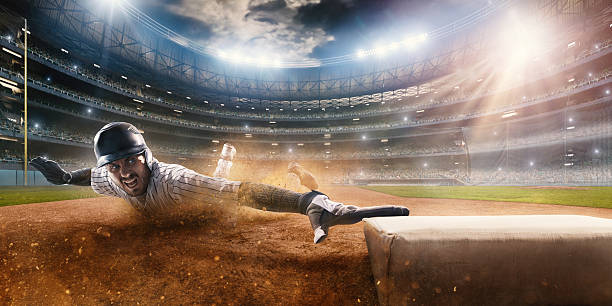 Sliding on third base Close up image of a baseball player sliding during a baseball game. He is wearing unbranded generic baseball uniform. The game takes place on outdoor baseball stadium full of spectators under stormy evening sky at sunset. The stadium is made in 3D. baseball sport stock pictures, royalty-free photos & images