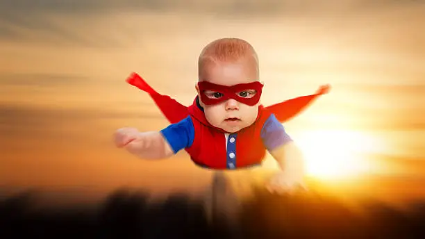 toddler little baby superman superhero with a red cape flying through the sky