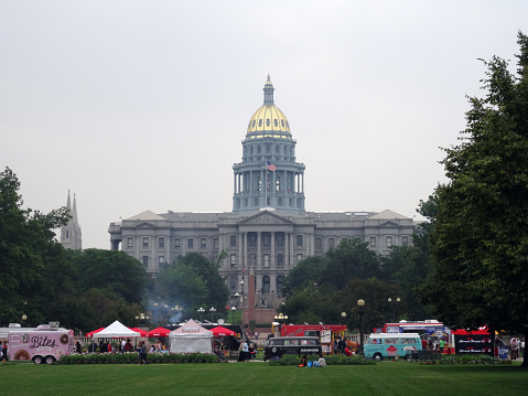 Devner, USA - July 7, 2015: People dine at Food Truck at Civic Center with capitol building in distance in Denver, Colorado.  July 7, 2015.