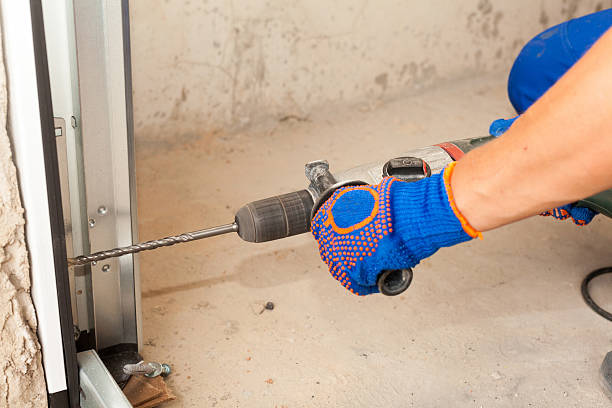 istock Garage doors installation. Worker drills a hole for the bolt 521978516
