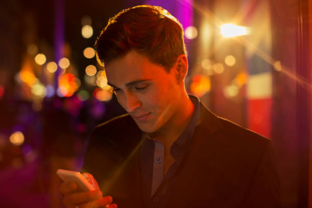 istock Man using cell phone on city street at night 521980451