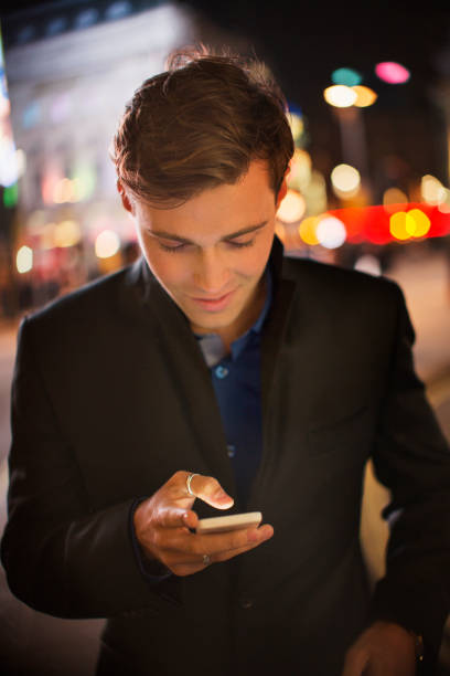 istock Man using cell phone on city street at night 521980483