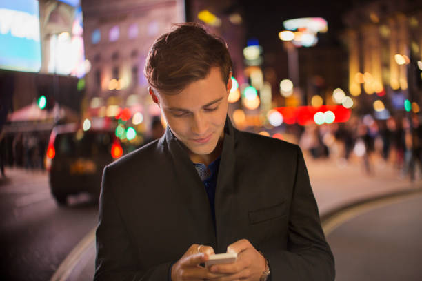 istock Man using cell phone on city street at night 521980539
