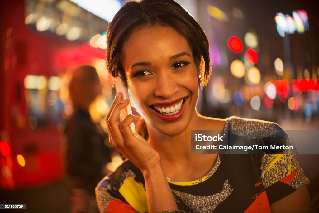 Woman taking on cell phone on city street at night  25-29 Years Stock Photo
