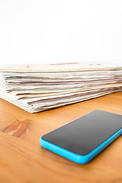 stos gazet i telefon komórkowy odizolowany na stół z drewna - single word text text messaging paper zdjęcia i obrazy z banku zdjęć