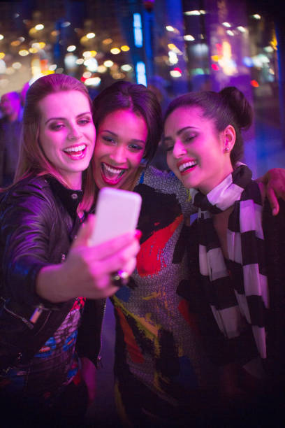 istock Women talking picture together using cell phone at night 521980937