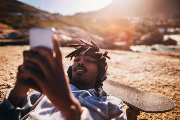 istock African American Resting and Looking at Smartphone at Seaside 521984302