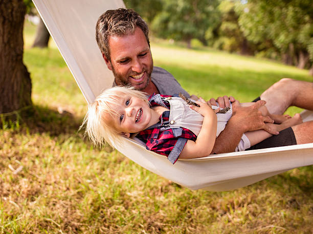 istock Cheerful dad cuddling his son on a white hammock 521985404