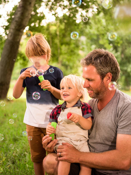 istock Father and sons having fun with soap bubbles outside 521985512