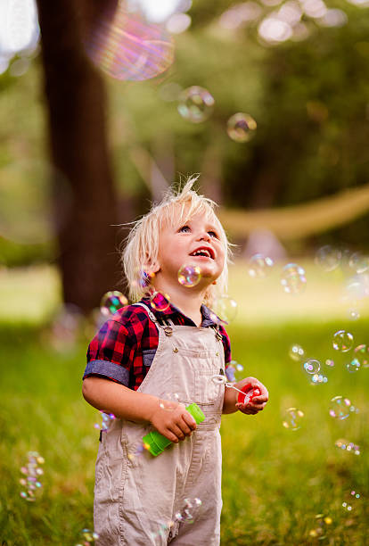istock Blonde boy getting excited with soap bubbles at the park 521985608