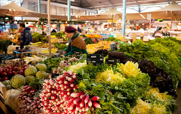 Vegetable stand at Les Halles farmer's market in Dijon, France Dijon, France - April 8, 2016: Sellers and shoppers at the famous burgundy Les Halles farmer's market in Dijon, France.  dijon stock pictures, royalty-free photos & images