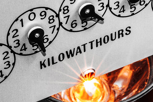 Kilowatthour electric meter register dials with light bulb shining below Macro close-up view of kilowatt hour electric meter register dials illuminated from below with light rays from energized electric light bulb   kilowatt stock pictures, royalty-free photos & images