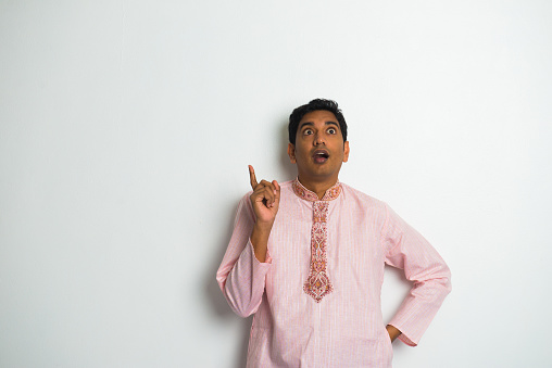 shocked indian male in traditional clothing and plain background