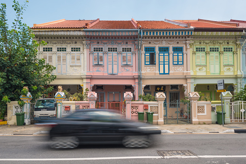 Singapore, Singapore - April 16, 2016: Black moving car with motion blur in front of colourful conservation shophouses along Koon Seng Road near Joo Chiat in Singapore. The image was taken early afternoon. 