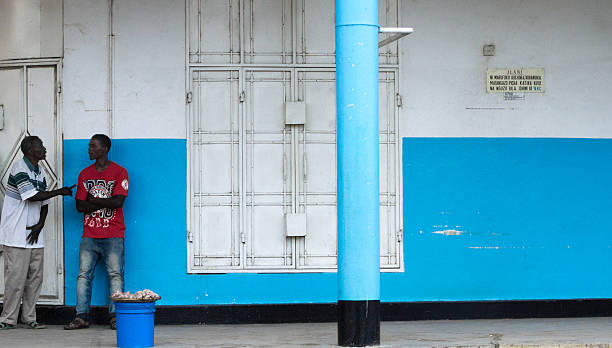 Mwanza, Tanzania: Vendors Against Blue Wall Mwanza, Tanzania - May 10, 2012: Two vendors chat against a blue wall in downtown Mwanza. mwanza city tanzania stock pictures, royalty-free photos & images