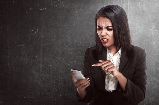 Asian business woman angry looking text on her cellphone