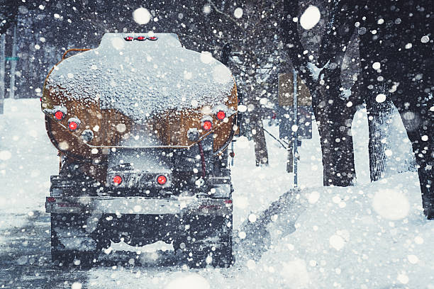 Heating Oil Truck A home heating oil delivery truck is parked on a city street during a heavy snowfall.  Composite image. fuel truck photos stock pictures, royalty-free photos & images