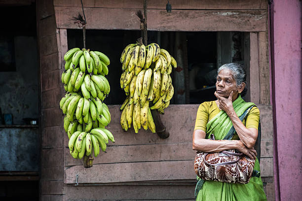 senior donna indiana vendita di banane sul ciglio della strada in india rurale - women poverty senior adult mature adult foto e immagini stock
