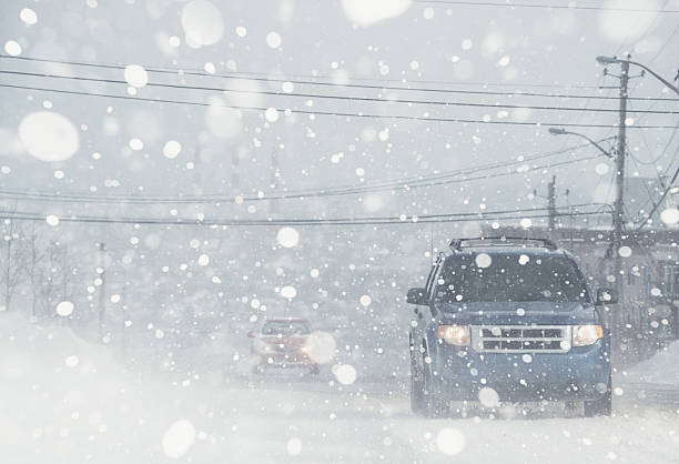 Whiteout Conditions Motorists navigate a city street in white out conditions. blizzard photos stock pictures, royalty-free photos & images