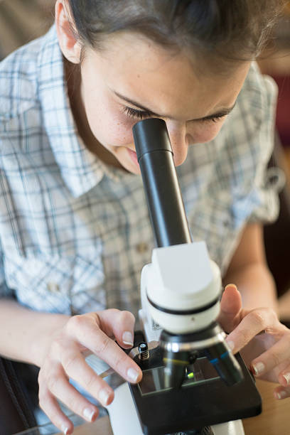 istock Teenage girl make homework scientific project with microscope 521999392