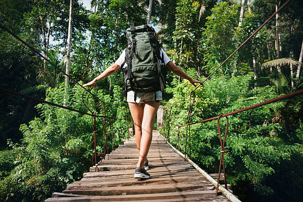 istock Woman with backpack traveling across bridge 521999970