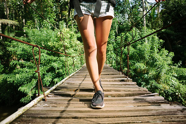 istock Woman's legs with backpack walking across hanging bridge 522000134