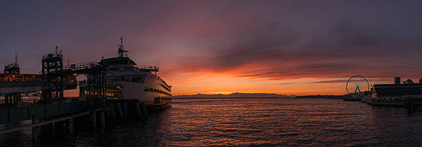Beautiful Commute Vivid sunset over Elliott bay with a Ferry docked on one side and the Ferris Wheel on the other. bainbridge island photos stock pictures, royalty-free photos & images