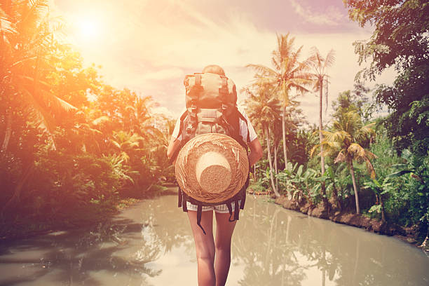 istock Woman with backpack standing near big tropical river 522001672
