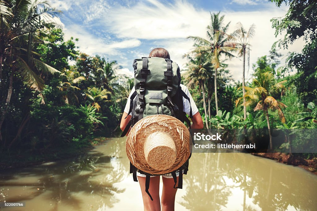 Woman standing near big tropical river Traveler woman with backpack standing near big tropical river at sunny day Travel Stock Photo