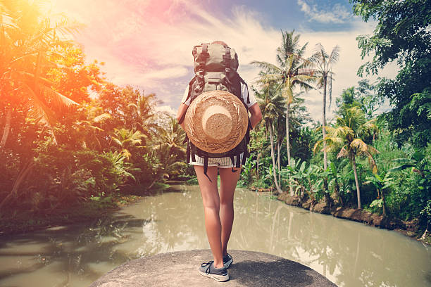 istock Woman with backpack standing near big tropical river 522001838