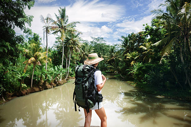 istock Risky woman with backpack standing near tropical river 522002158