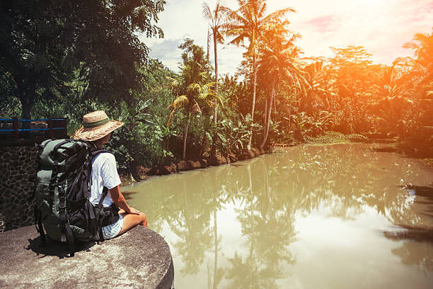 istock Brave woman with backpack sitting near tropical river 522002238