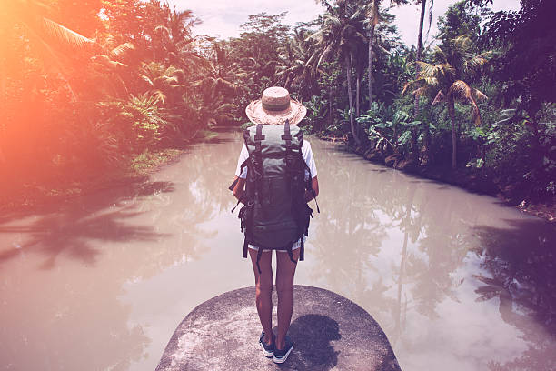 istock Woman with backpack looking at tropical river 522002722