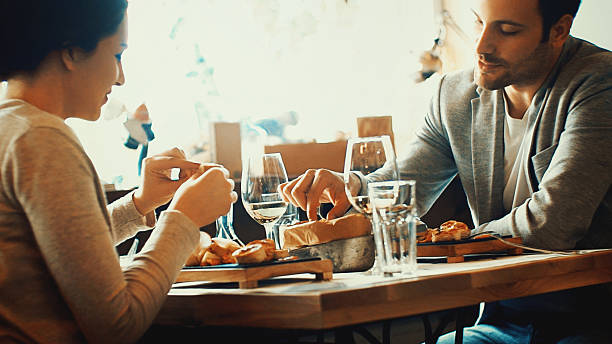 Closeup fo early 30's couple having lunch in a restaurant after shopping.  Sitting by window table.They are wearing beige colored casual clothes.