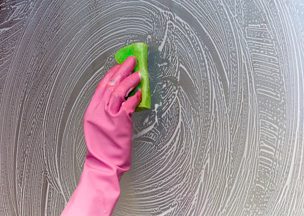 istock Hand in pink protective glove washing and cleaning window. 522005572