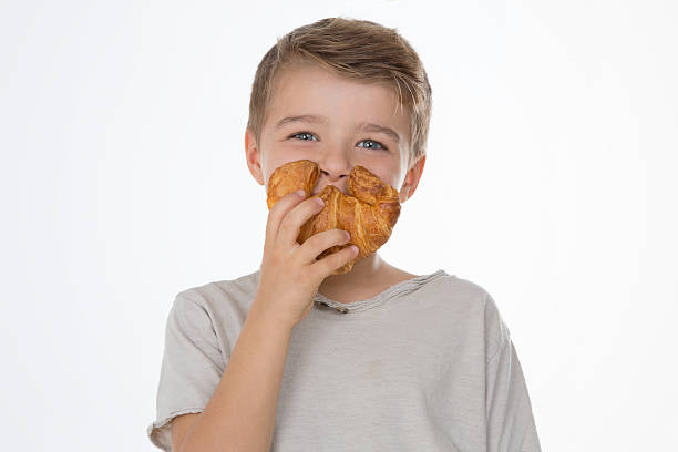 joking child kid smiles while showing a croissant little boys blue eyes blond hair one person stock pictures, royalty-free photos & images