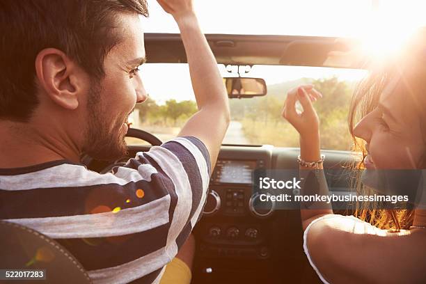 Giovane Coppia Di Guida Lungo La Strada Di Campagna In Auto Top Aperta - Fotografie stock e altre immagini di Relazione di coppia