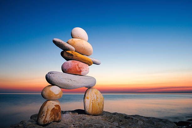 inukshuk Figure of inukshuk on the seacoast against the sunset cairns photos stock pictures, royalty-free photos & images