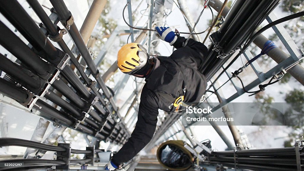 Telecommunication manual high worker engineer repairing antenna Telecommunication manual high worker engineer repairing 260 feet tall mobile base station (communication tower), high angle of view.  Construction Industry Stock Photo
