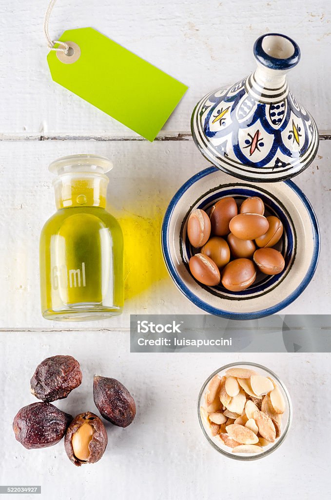 Dadi e olio di Argan su bianco sul tavolo con l'etichetta verde - Foto stock royalty-free di Africa