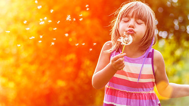istock Little girl blowing a dandelion 522035375