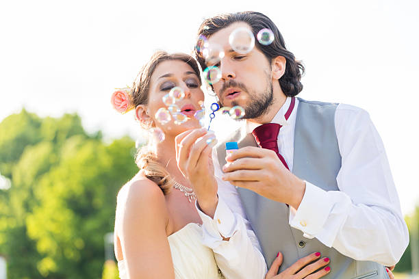 istock Wedding bride and groom blowing bubbles outside on field 522050905