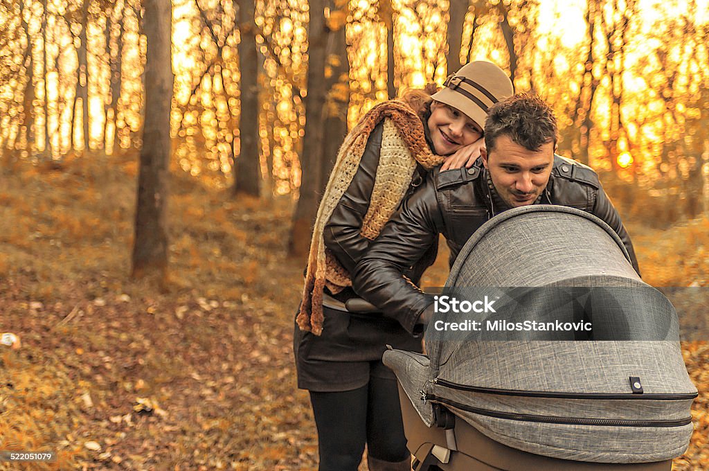 Happy family in the park in autumn day Happy family in the park with a baby stroller on autumn day Adult Stock Photo