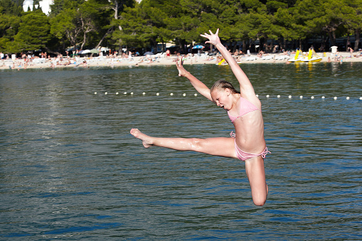 Girl jumping in the sea on background of coast