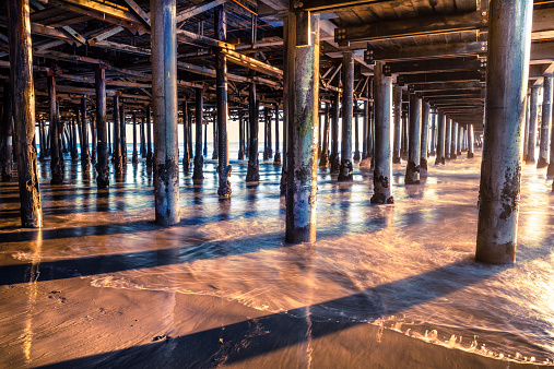 Underneath the Santa Monica Pier at sunset as the tide is moving out.