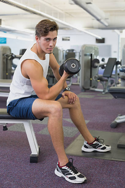 istock Fit man lifting dumbbells sitting on the bench 522117153
