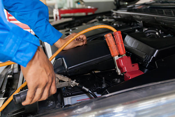 istock Mechanic attaching jumper cables with battery car - closeup 522121278